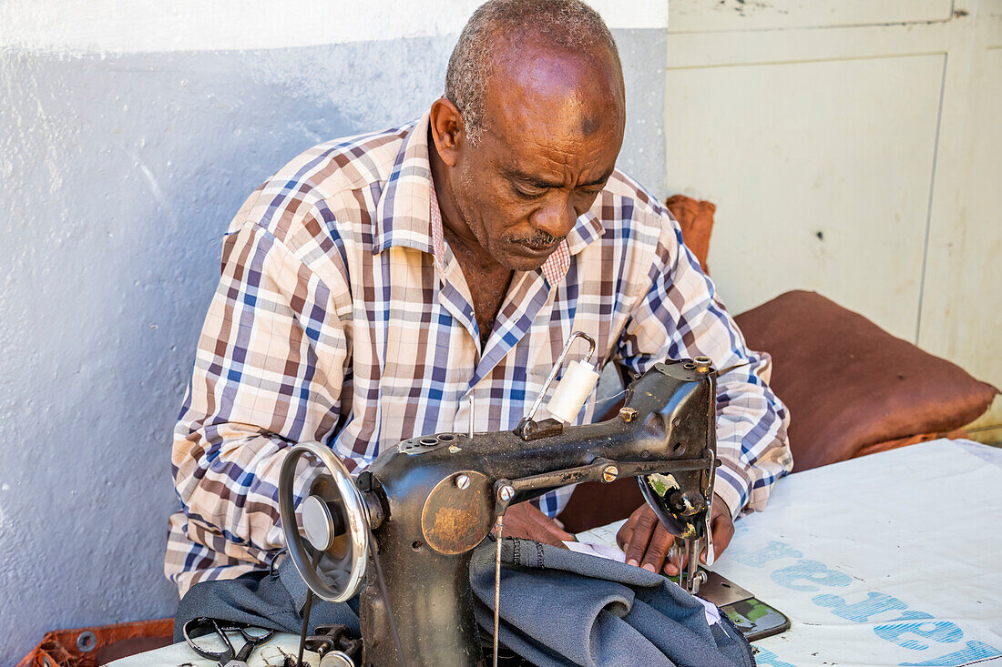 Tailor working on a vintage sewing machine in Harar Jugol, the Fortified Historic Town; Harar, Harari Region, Ethiopia