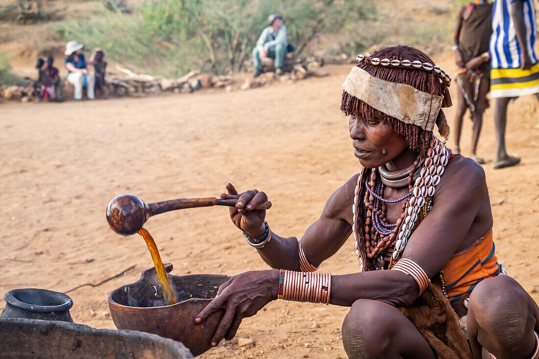 Hamer-Frau bei der Zubereitung eines zeremoniellen Getränks während einer Stiersprungzeremonie, mit der ein Junge in die Männlichkeit eingeführt wird, im Dorf Asile, Omo-Tal; Region der Nationalitäten und Völker des Südens, Äthiopien