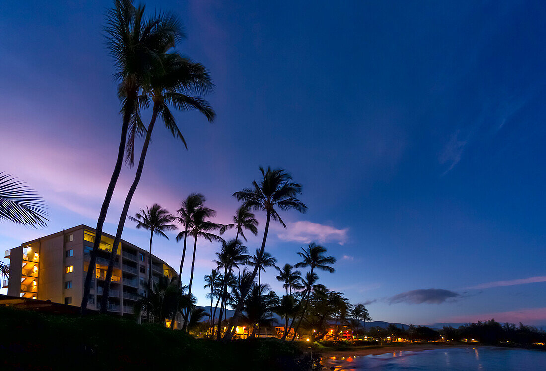 Hotels und Palmen entlang der Küstenlinie bei Sonnenuntergang, Kamaole One und Two Strände, Kamaole Beach Park; Kihei, Maui, Hawaii, Vereinigte Staaten von Amerika