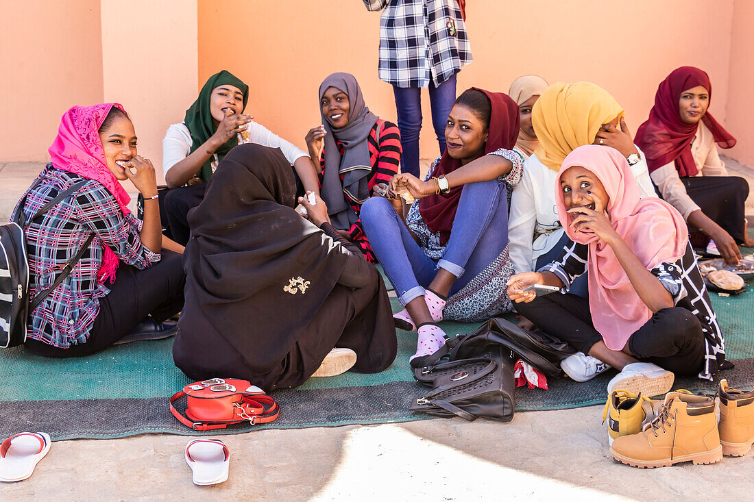 Junge sudanesische Frauen, die auf dem Boden sitzen und gemeinsam essen; Kerma, Nordstaat, Sudan