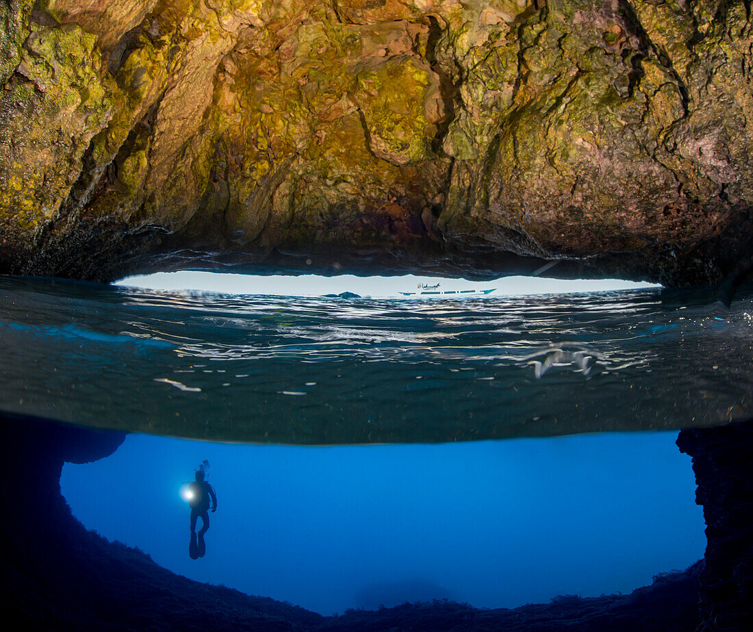 Halb oben, halb unten Aufnahme eines Tauchers am Eingang zu einer Höhle, die die Oberfläche auf der Insel Gato, Bohol Sea, Südostasien, durchbricht; Philippinen