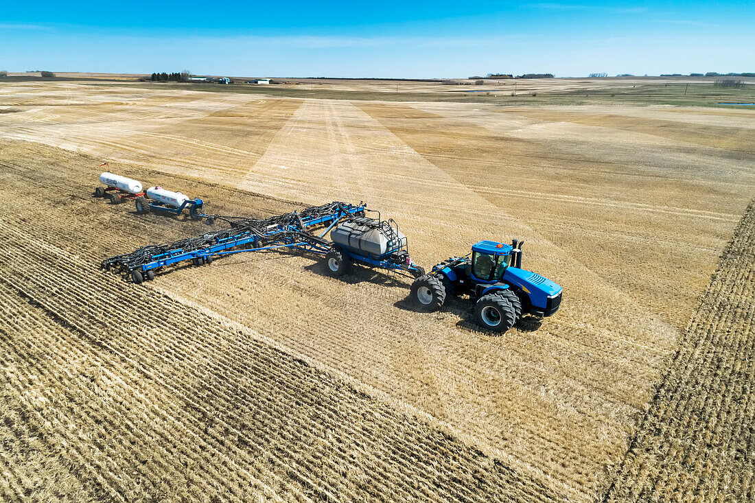 Air seeder in field with white ammonia tanks, near Beiseker; Alberta, Canada