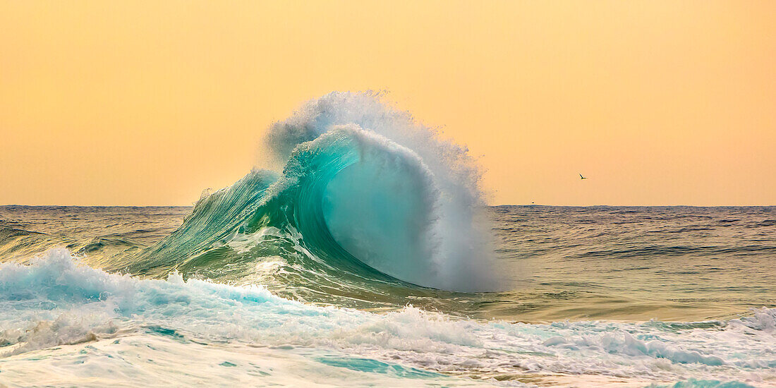 Ocean waves crashing into the shore off the Na Pali coast at sunset; Kauai, Hawaii, United States of America