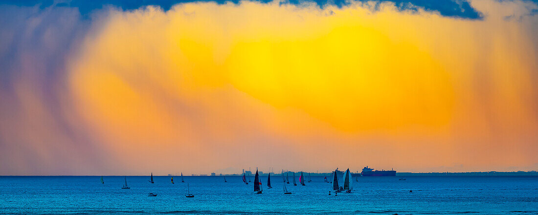 Hellgelb leuchtende Wolken bei Sonnenuntergang vor Waikiki Beach mit einem Segelboot im Wasser; Honolulu, Oahu, Hawaii, Vereinigte Staaten von Amerika