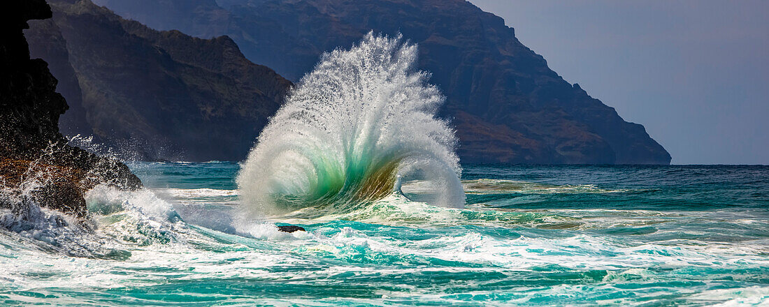 Large ocean wave crashes into rock along the Na Pali Coast; Kauai, Hawaii, United States of America