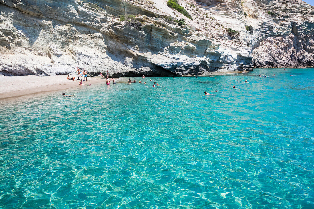 Touristen schwimmen im klaren, türkisfarbenen Wasser der Bucht von Galazia Nera; Insel Polyaigos, Kykladen, Griechenland