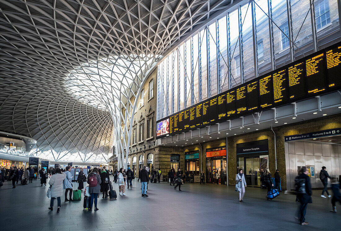 Innenraum des Londoner Bahnhofs King's Cross mit Reisenden und Geschäften; London, England