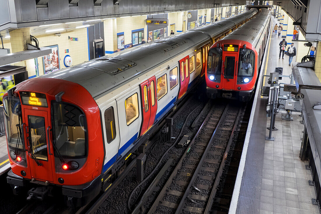 Tube Station with trains on the tracks and passengers on the platform waiting; London, England