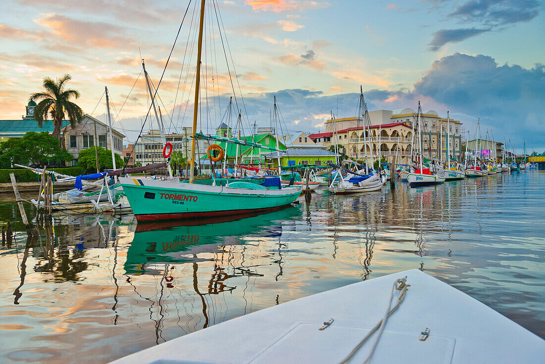 Colourful waterfront of Belize City at dusk with reflections in the tranquil water; Belize City, Belize District, Belize