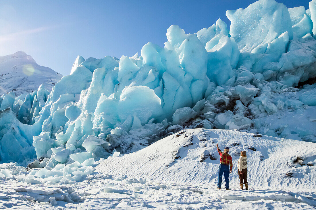 Hikers on the edge of frozen Portage Lake and looking at the Portage Glacier ice, South-central Alaska and South of Anchorage; Alaska, United States of America