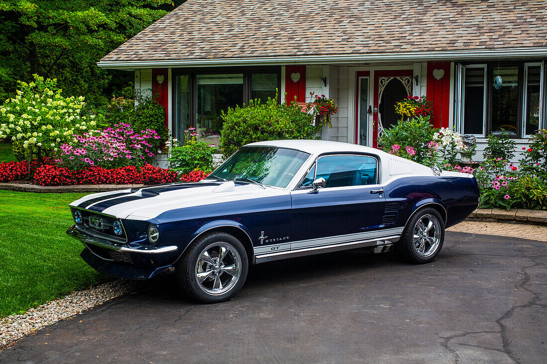 Sports car parked outside a house with blossoming flowers; Hudson, Quebec, Canada