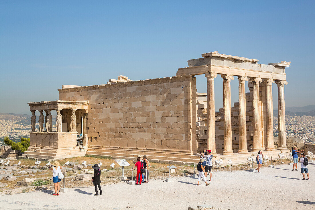 Tourists sightseeing at the Temple of Erectheion, Acropolis of Athens, archaeological site with ruins; Athens, Greece