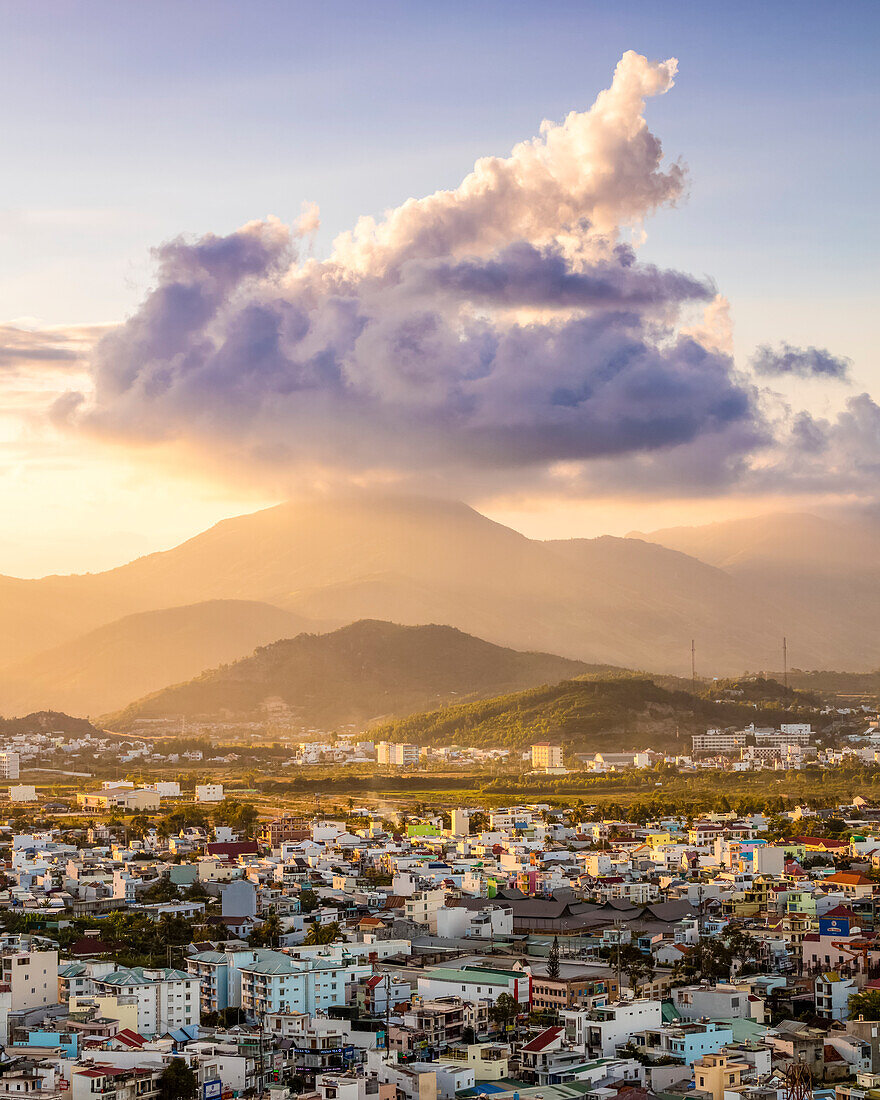 Glowing sunset over the mountains and cityscape of Nha Trang;, with a large cloud formation sitting over the mountains; Nha Trang, Khanh Hoa Province, Vietnam