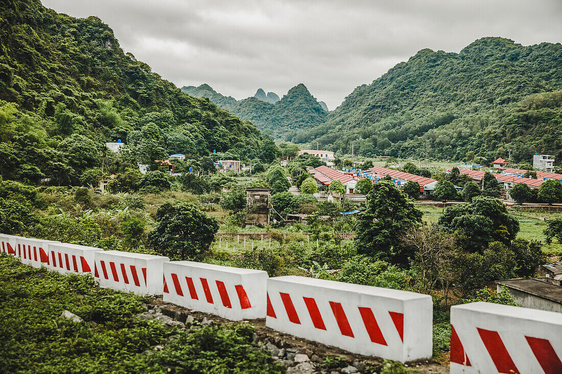Barriers across the landscape with a town and lush foliage covering the karst limestone formations; Cat Ba island, Vietnam