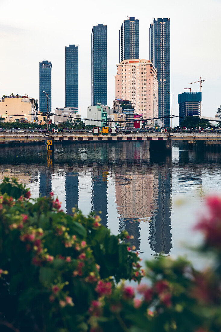Skyscrapers in a row form the skyline and reflect in the water of the Saigon River; Ho Chi Minh City, Vietnam