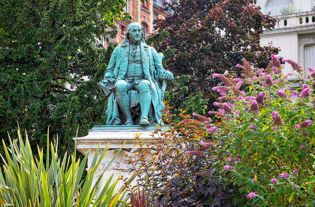 Benjamin Franklin statue in a garden with trees and blossoming plants; Paris, France