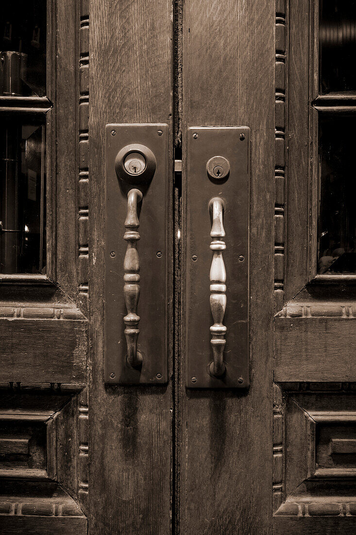 Long door handles and locks on a set of double wooden doors with carved decorative designs; Franklin, Tennessee, United States of America