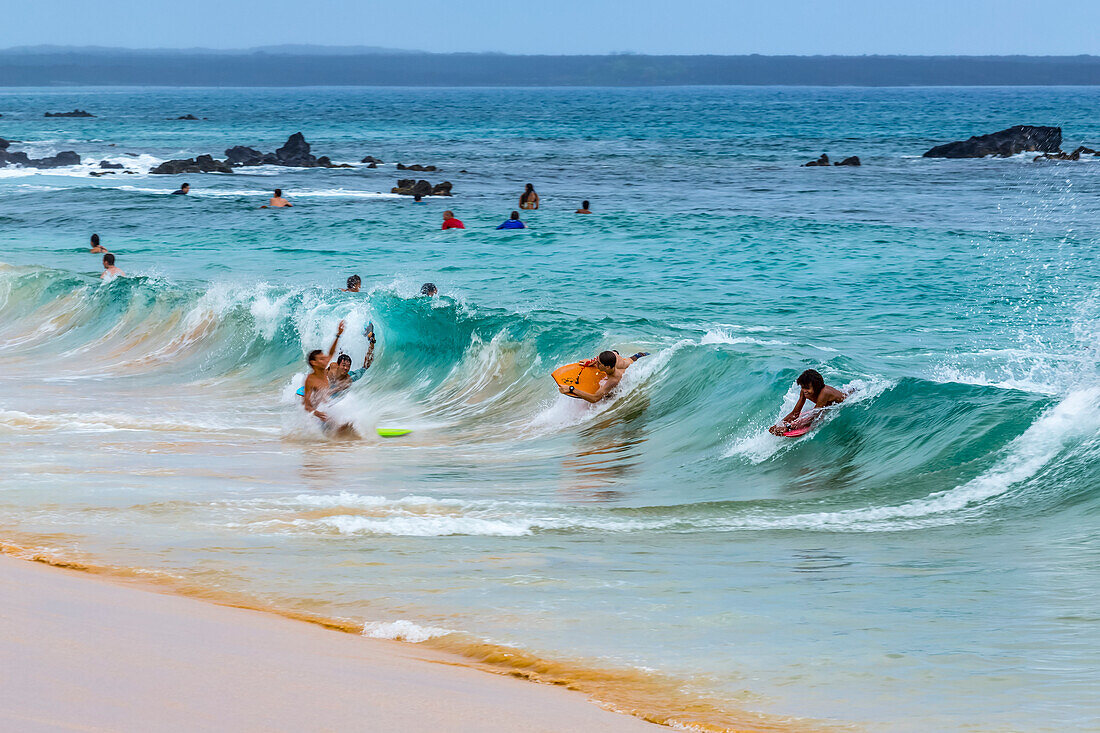 Surfers and body boarders play in the surf waves on Makena beach in on Maui, Hawaii, a popular tourist beach near Kihei on the pacific ocean and a destination for family travellers; Kihei, Maui, Hawaii, United States of America