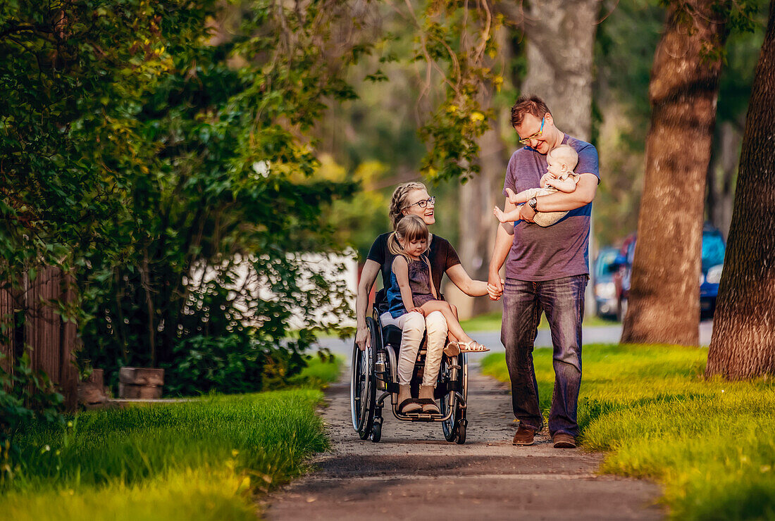 Eine Familie beim abendlichen Spaziergang, die Mutter ist querschnittsgelähmt und sitzt im Rollstuhl; Edmonton, Alberta, Kanada