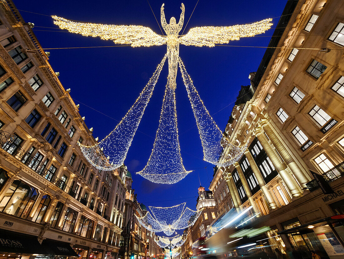 Beleuchtete Engel hängen über einer Straße in London in der Abenddämmerung zur Weihnachtszeit; London, England