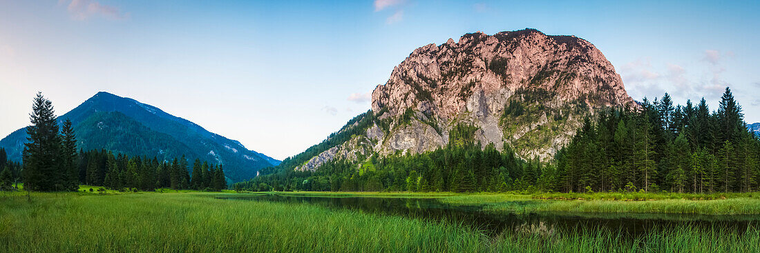 Cliff face on alpine mountain being hit with a summer evening sun, overlooking a lake and forest; Wildaplen, Landl, Austria