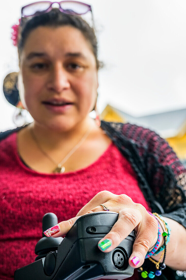 Maori-Frau mit Cerebralparese in einem Rollstuhl, Fingernägel mit Nagelkunst; Wellington, Neuseeland