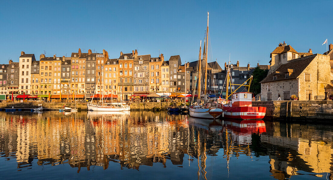 Boats and buildings reflected in the tranquil water of the harbour; Honfleur, Normandy, France