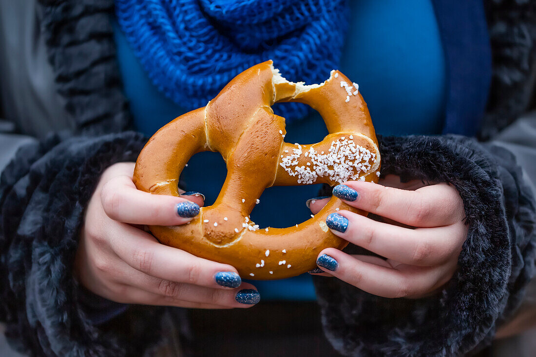 Frau isst eine Brezel; New York City, New York, Vereinigte Staaten von Amerika