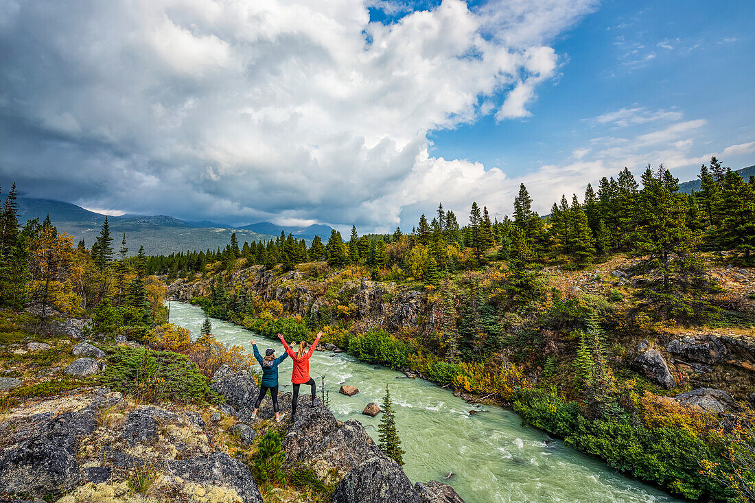Two women standing overlooking the Tutshi River near the Yukon/British Columbia border; Yukon, Canada