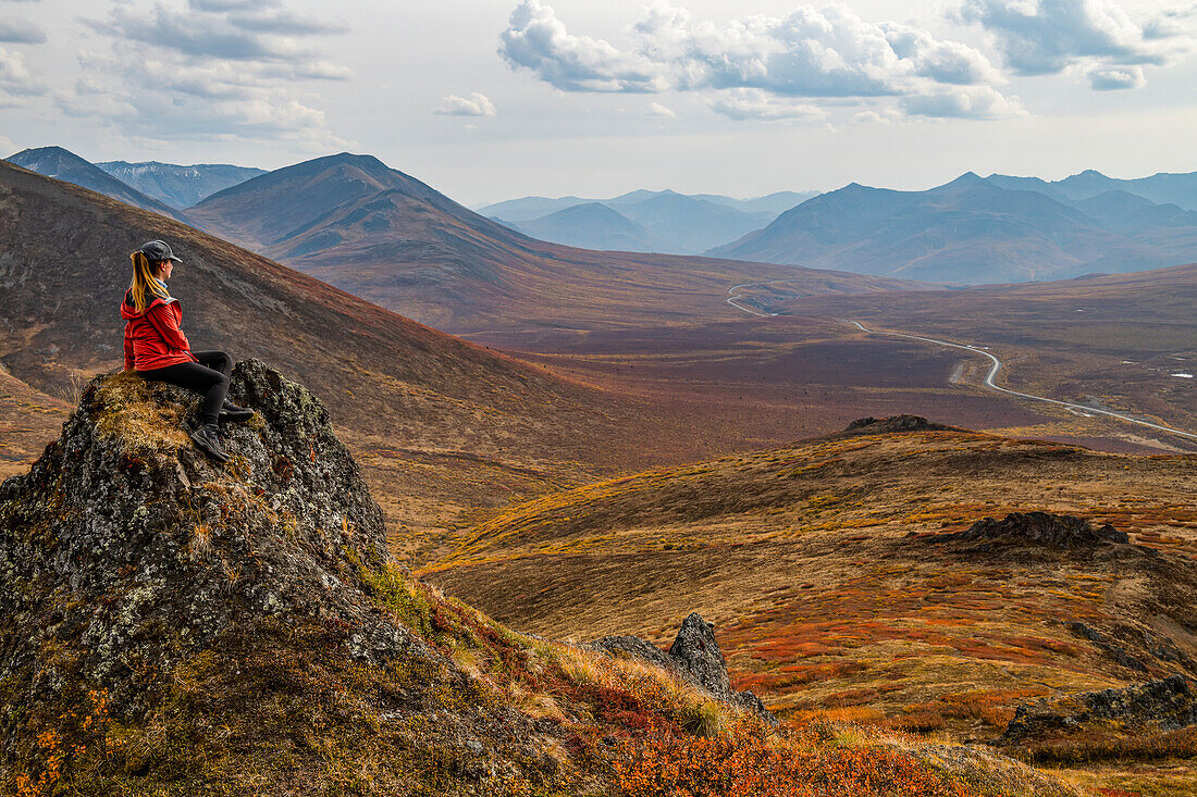 Frau erkundet die Berge entlang des Dempster Highway im Herbst; Yukon, Kanada