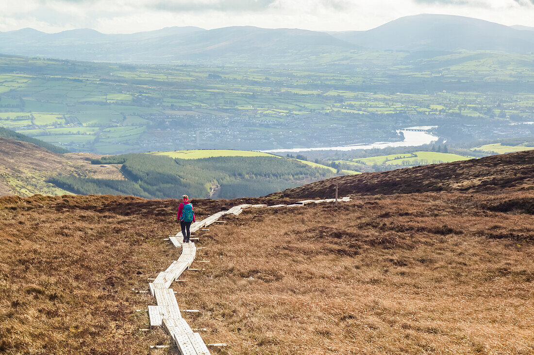 Holzbohlenweg, der über ein Moor auf einem Berg mit einem Fluss und Feldern in der Ferne führt; Killaloe, Clounty Clare, Irland