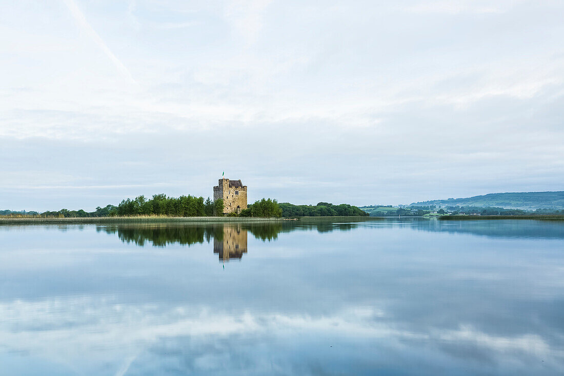 Symmetrische Spiegelungen des Castlebawn Tower House am Lough Derg an einem Sommertag; Scariff, Grafschaft Clare, Irland