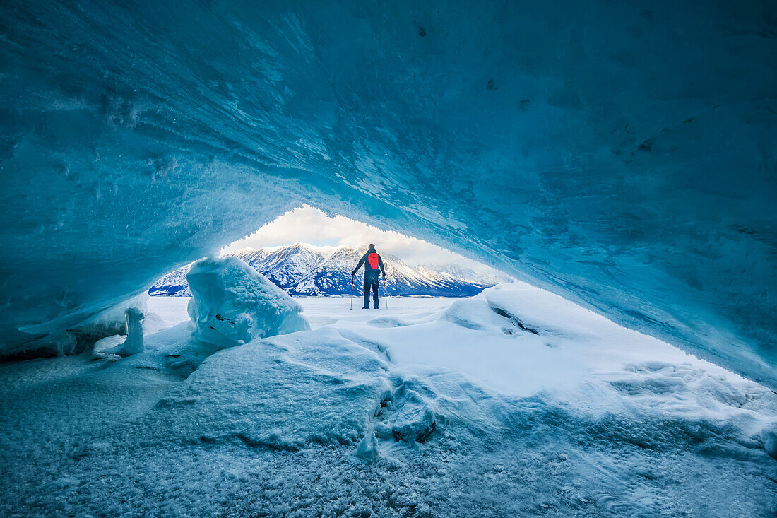 An der Küste des Kluane-Nationalparks nimmt zerkleinertes Eis wunderschöne Muster und Formen an.  Ein Mann mit Trekkingstöcken steht und schaut auf den zugefrorenen See; Haines Junction, Yukon, Kanada