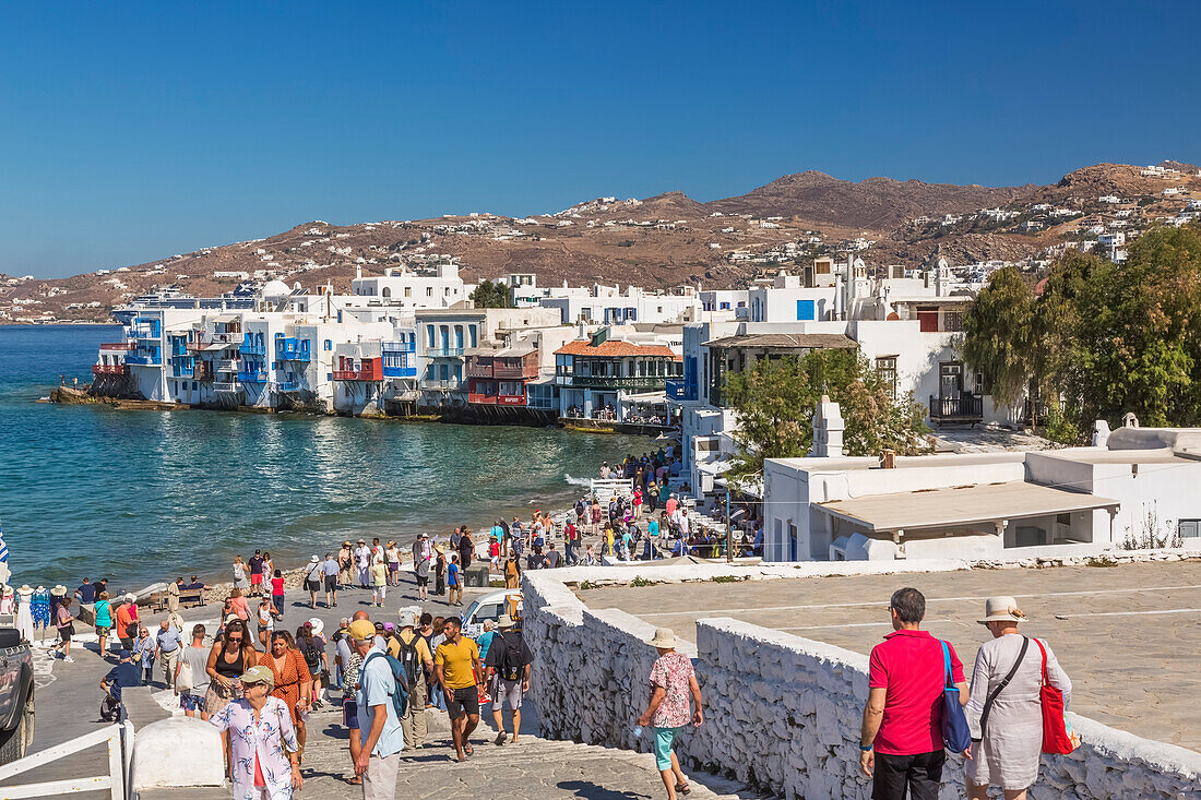 Tourists on boardwalk leading down to waterfront houses in Little Venice area of Mykonos Town; Mykonos Town, Mykonos Island, Greece