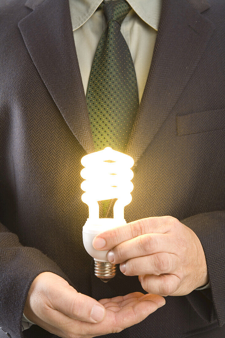 Geschäftsmann hält beleuchtete Energiesparlampe