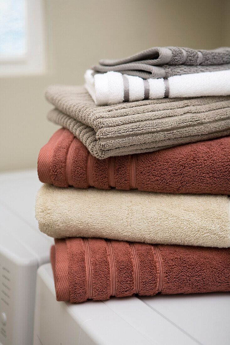 Stapel sauberer Handtücher auf der Waschmaschine und dem Trockner