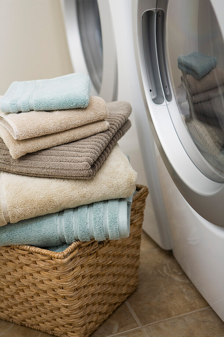 Stapel sauberer Handtücher neben der Waschmaschine und dem Trockner