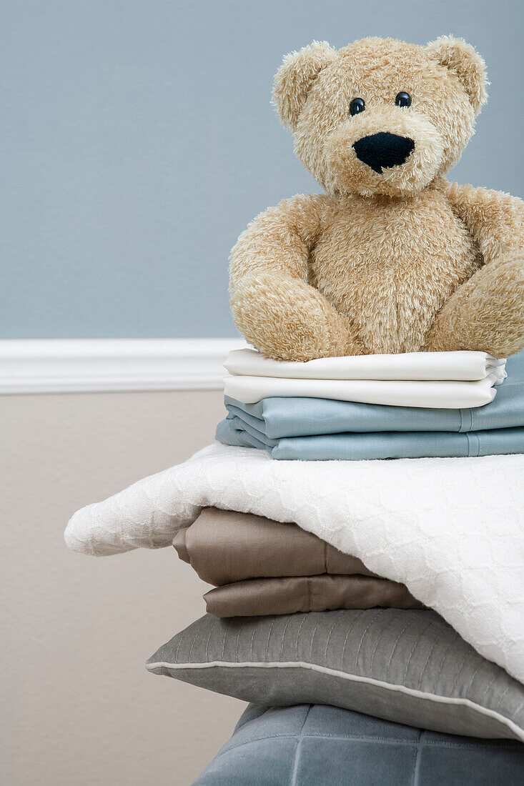 Stapel mit Bettwäsche und Teddybär