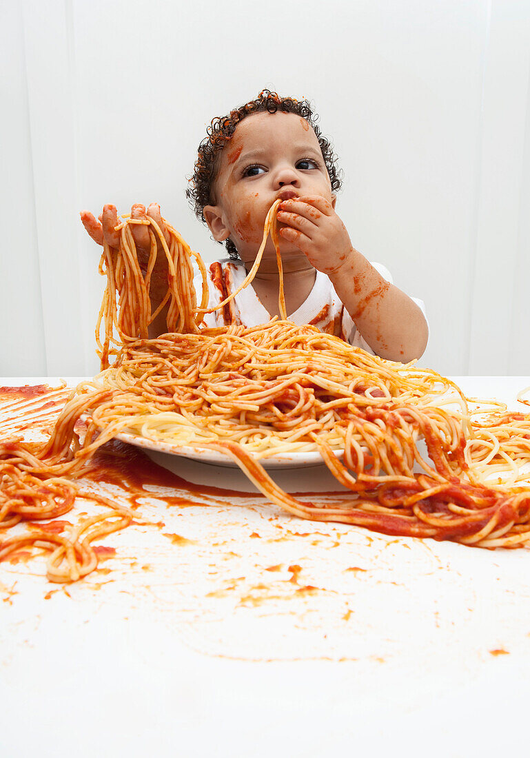 Junge isst Spaghetti mit den Händen