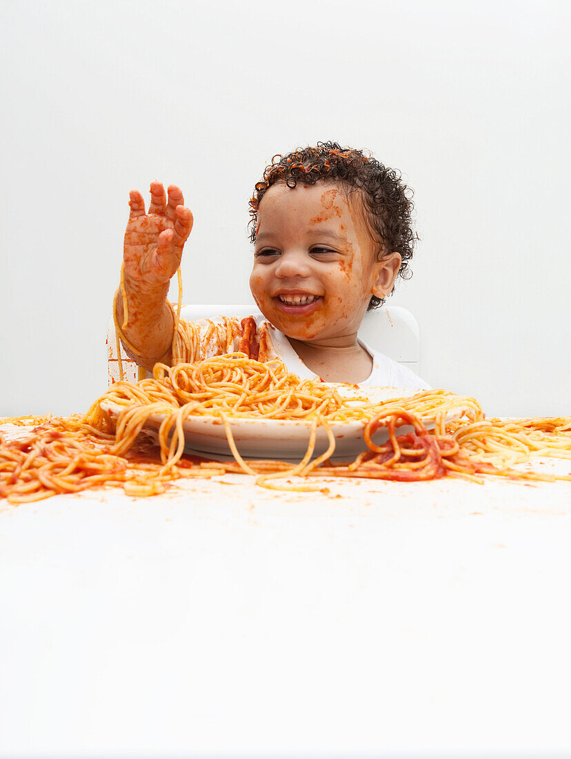 Junge isst Spaghetti mit Händen