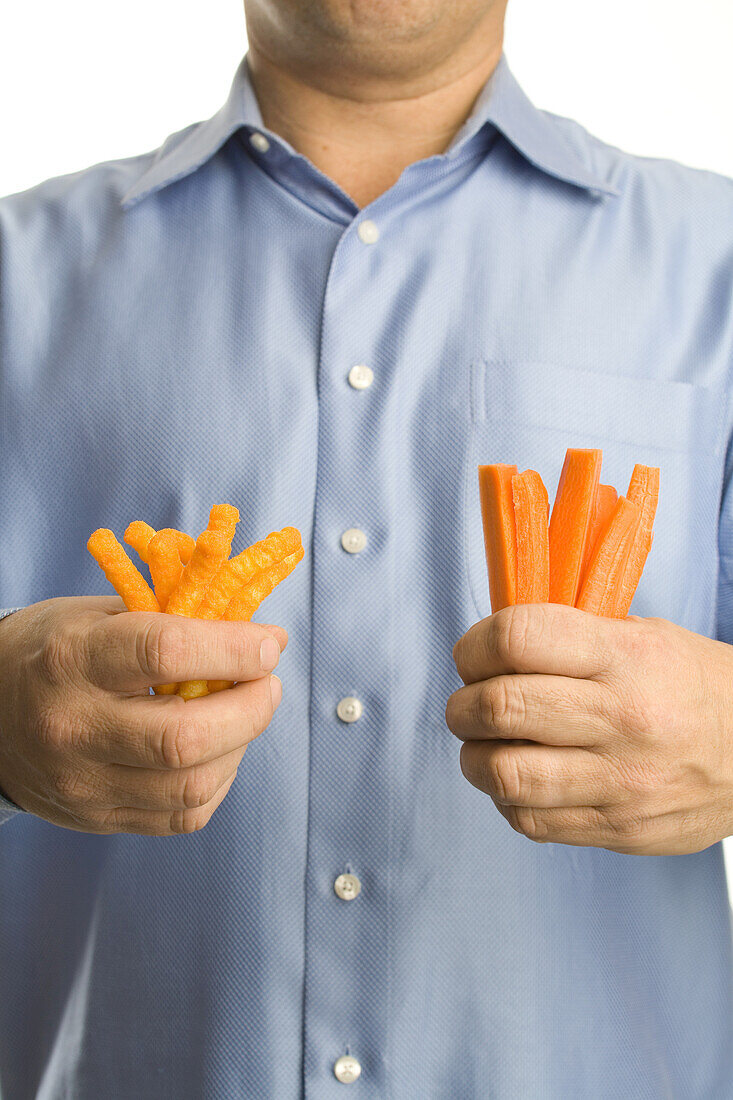 Man Holding Cheesies in One Hand and Carrot Sticks in the Other