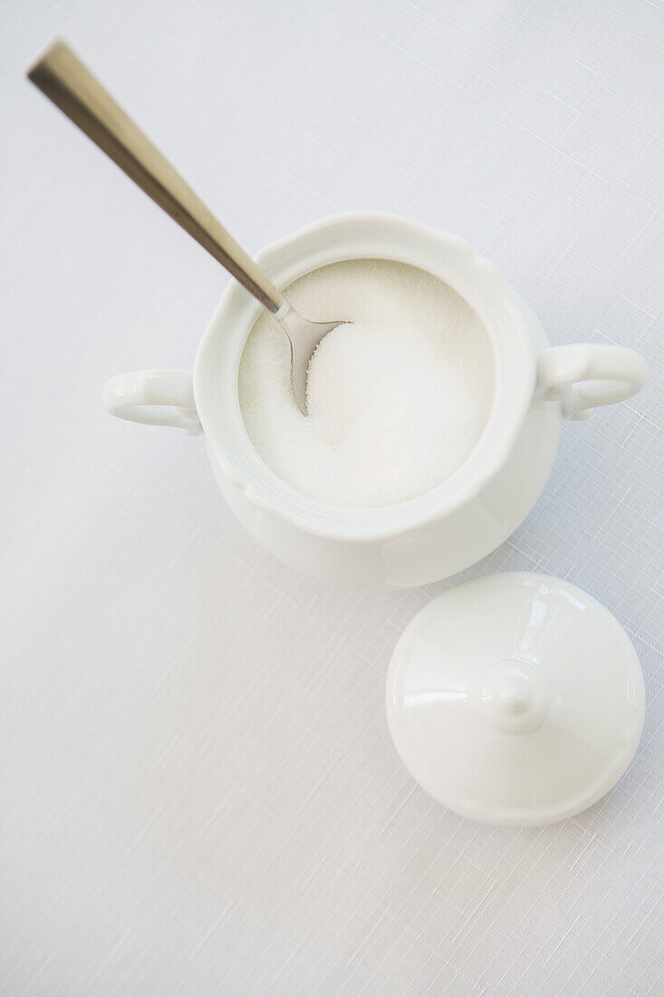 White porcelain sugar bowl with sugar and spoon, studio shot