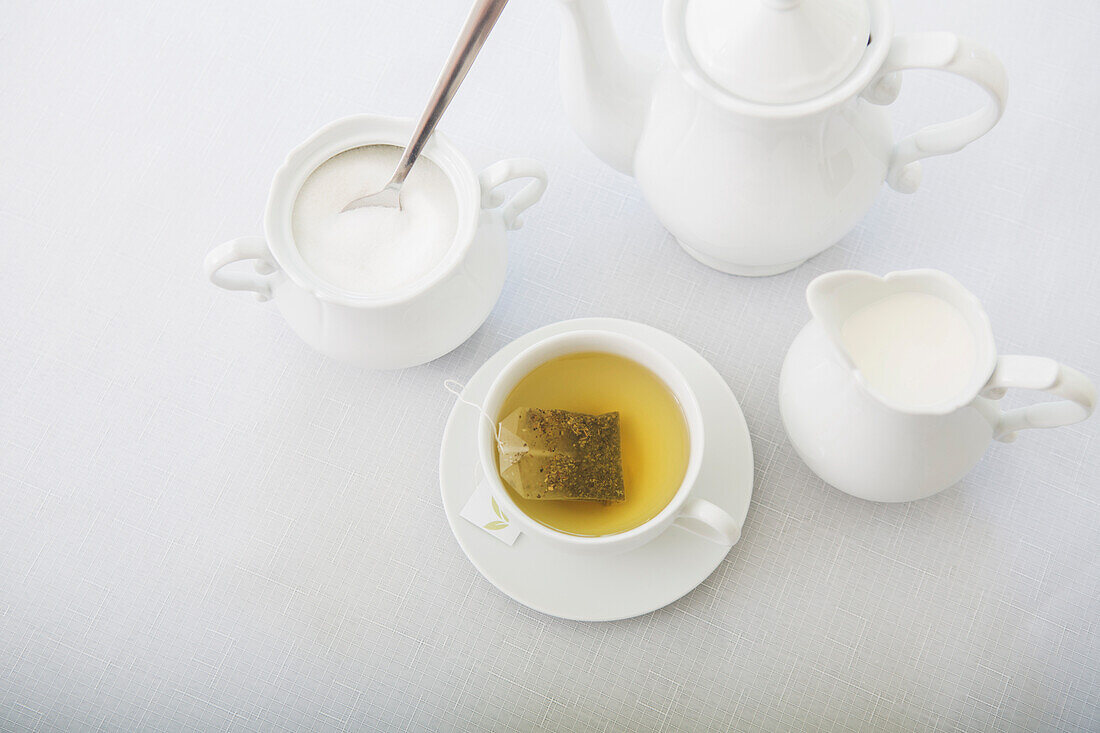 Teetasse aus weißem Porzellan mit Untertasse, Zuckerdose, Milchkännchen und Teekanne, Atelieraufnahme
