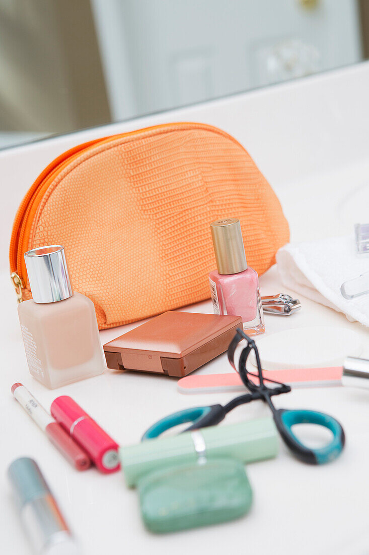 Women's cosmetic travel bag on bathroom counter, with makeup and other beauty products