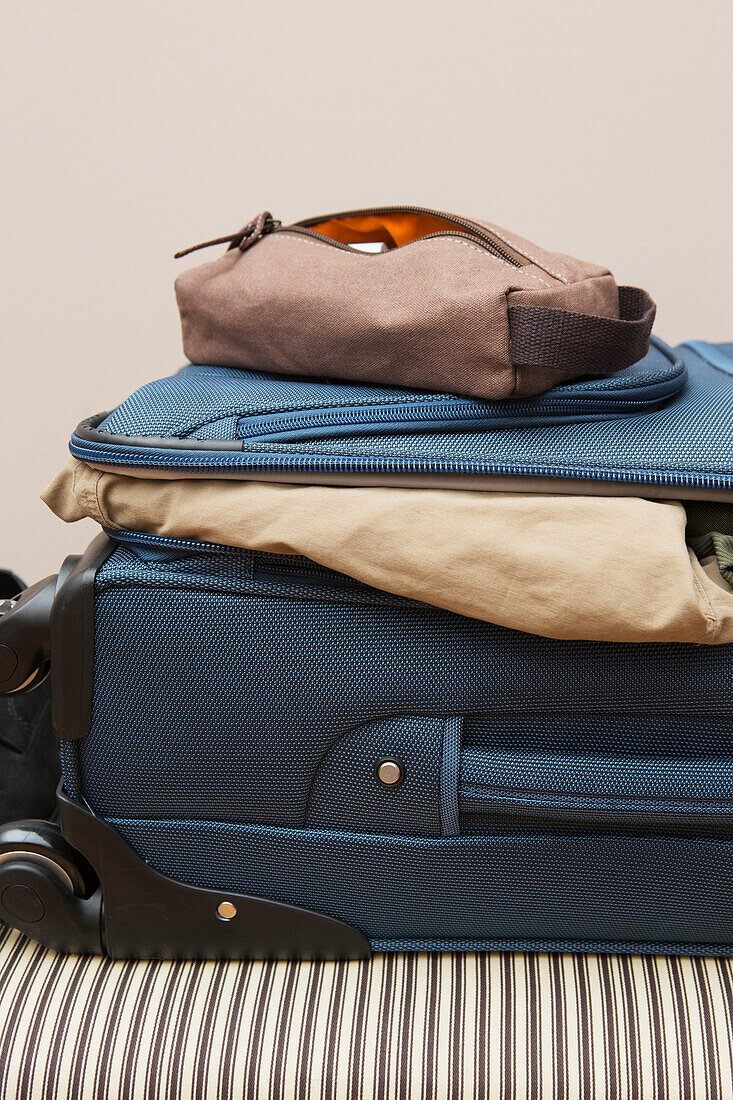Braune Herrenkulturtasche auf gepacktem Koffer auf dem Bett, USA