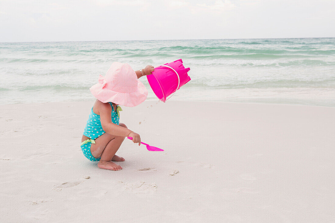 Kleines Mädchen spielt mit Schaufel und Eimer im Sand am Strand, Destin, Florida, USA