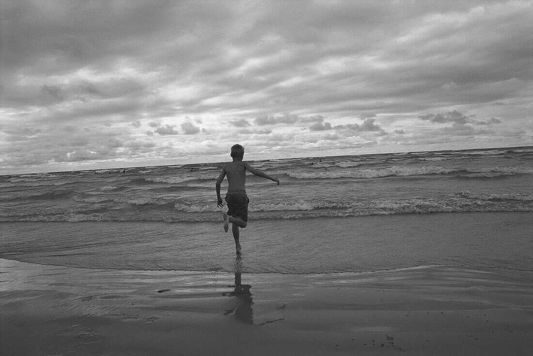 Back View of Boy Running in Surf On Beach
