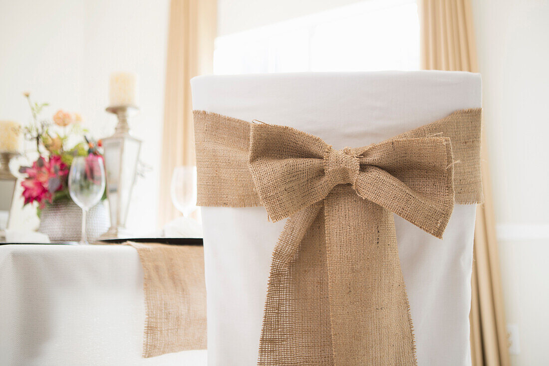 Back view of covered chair with sash and table setting for fine dining