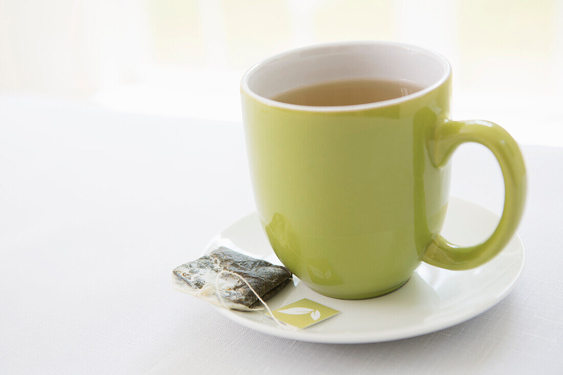 Gebrauchter Teebeutel auf Untertasse mit Teetasse in grüner Tasse, Studio Shot