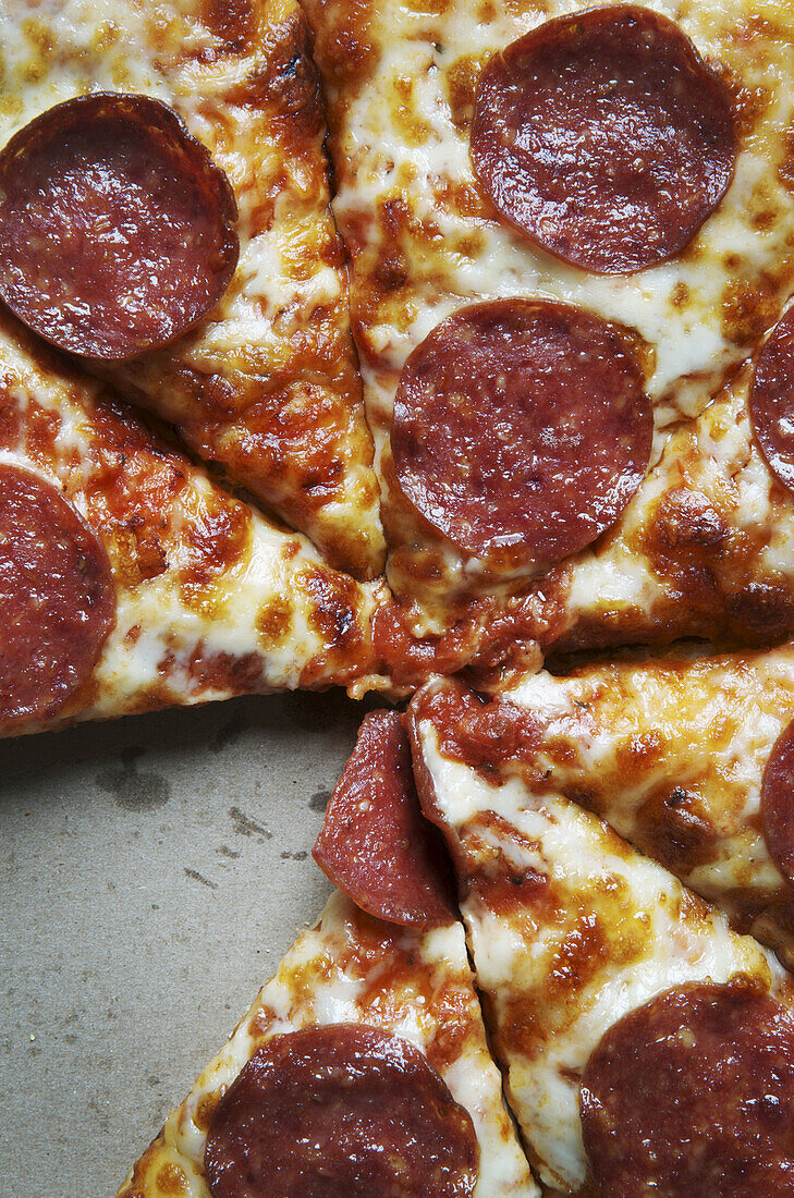 Draufsicht auf geschnittene Pepperoni-Pizza in einer Schachtel, ein Stück fehlt